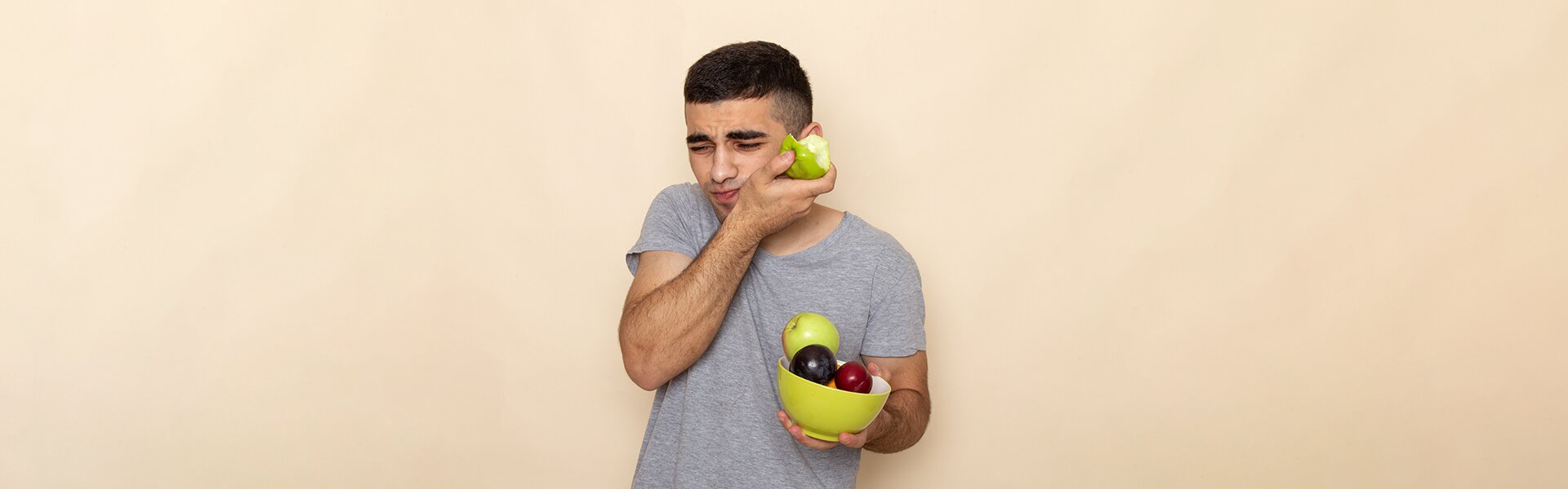 dentist patient model holding his jaw with apples in his hands
